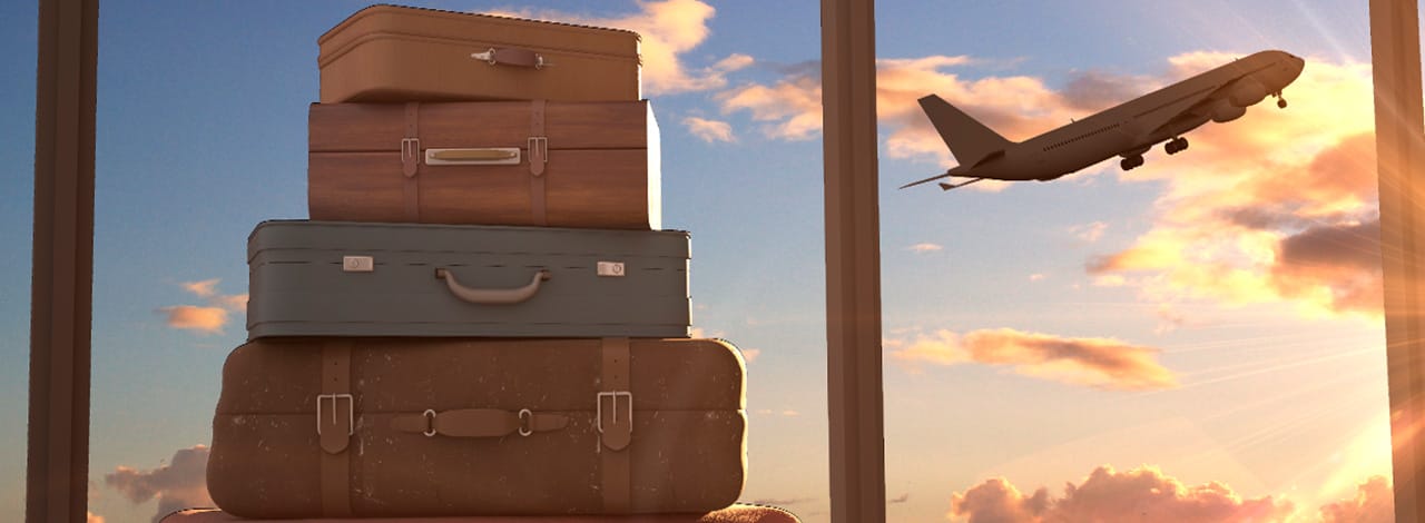 Una pila di valigie con un aereo in partenza sullo sfondo al tramonto
